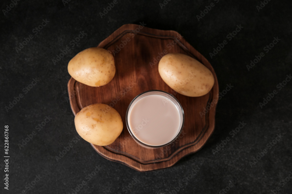 Glass of tasty potato milk on black background