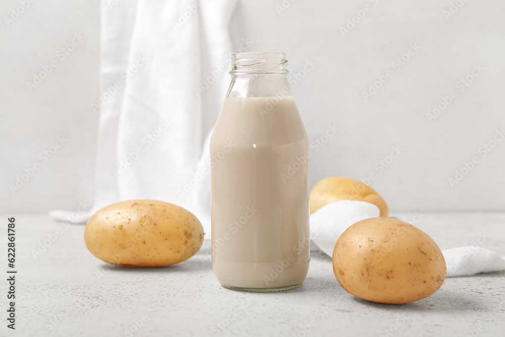 Bottle of tasty potato milk on light background