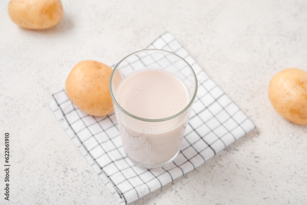 Glass of tasty potato milk on light background