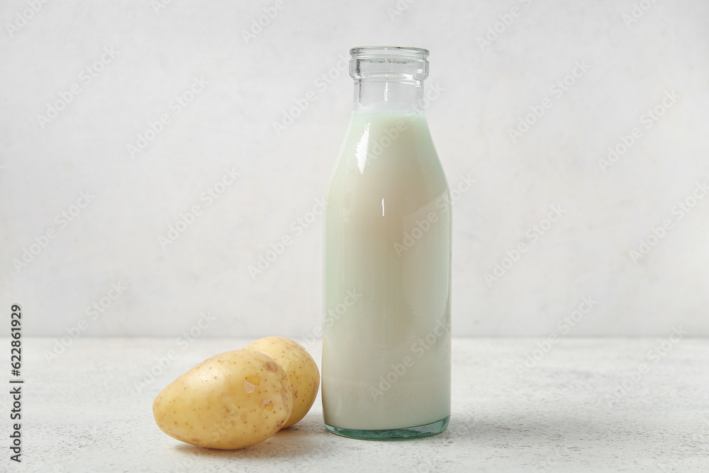 Bottle of tasty potato milk on light background