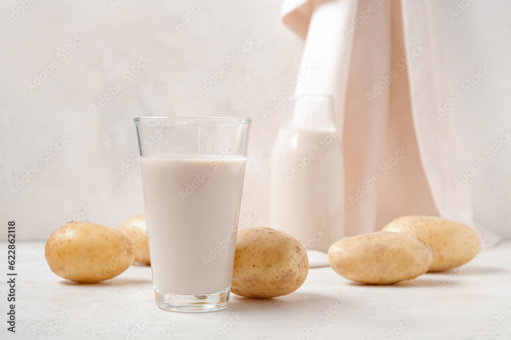 Glass of tasty potato milk on light background