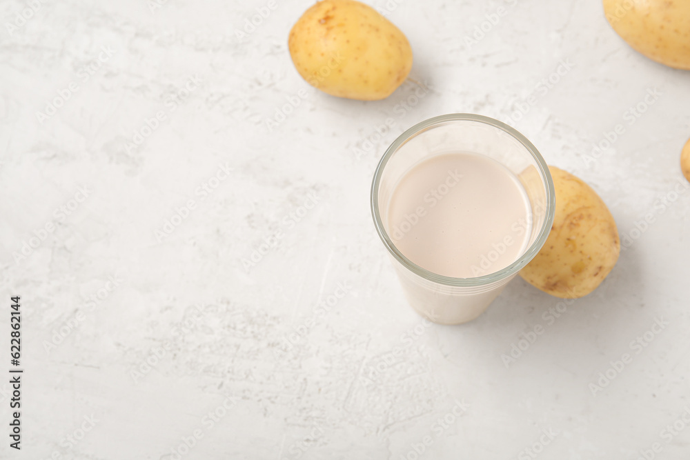 Glass of tasty potato milk on light background