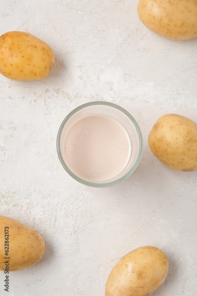 Glass of tasty potato milk on light background