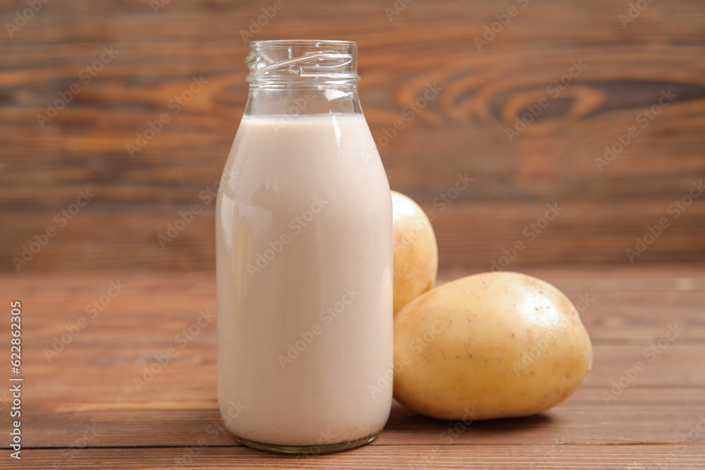 Bottle of tasty potato milk on wooden background