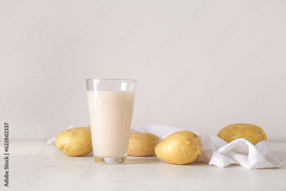 Glass of tasty potato milk on light background