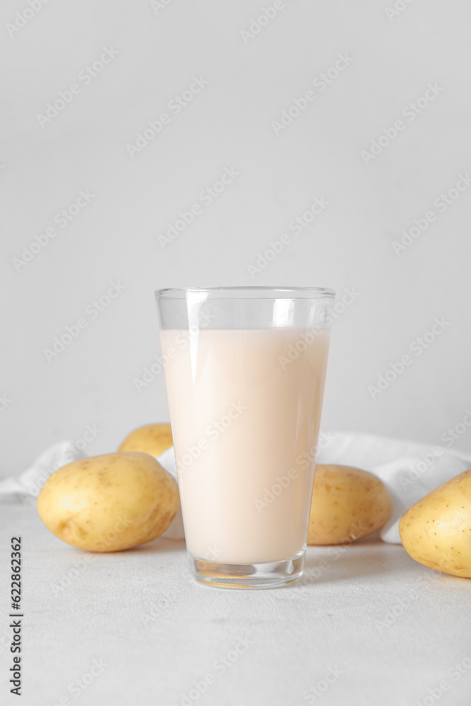 Glass of tasty potato milk on light background