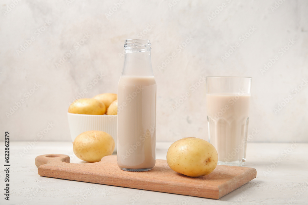 Bottle of tasty potato milk on light background