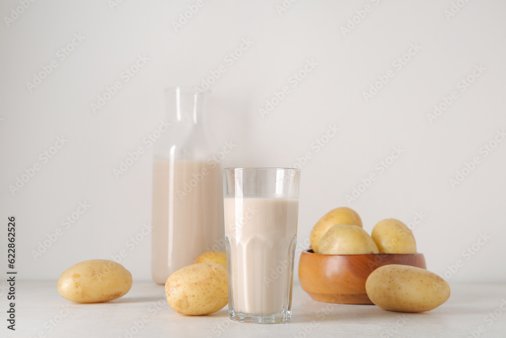 Glass of tasty potato milk on light background