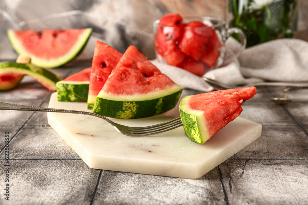 Board with pieces of fresh watermelon on grey tile table