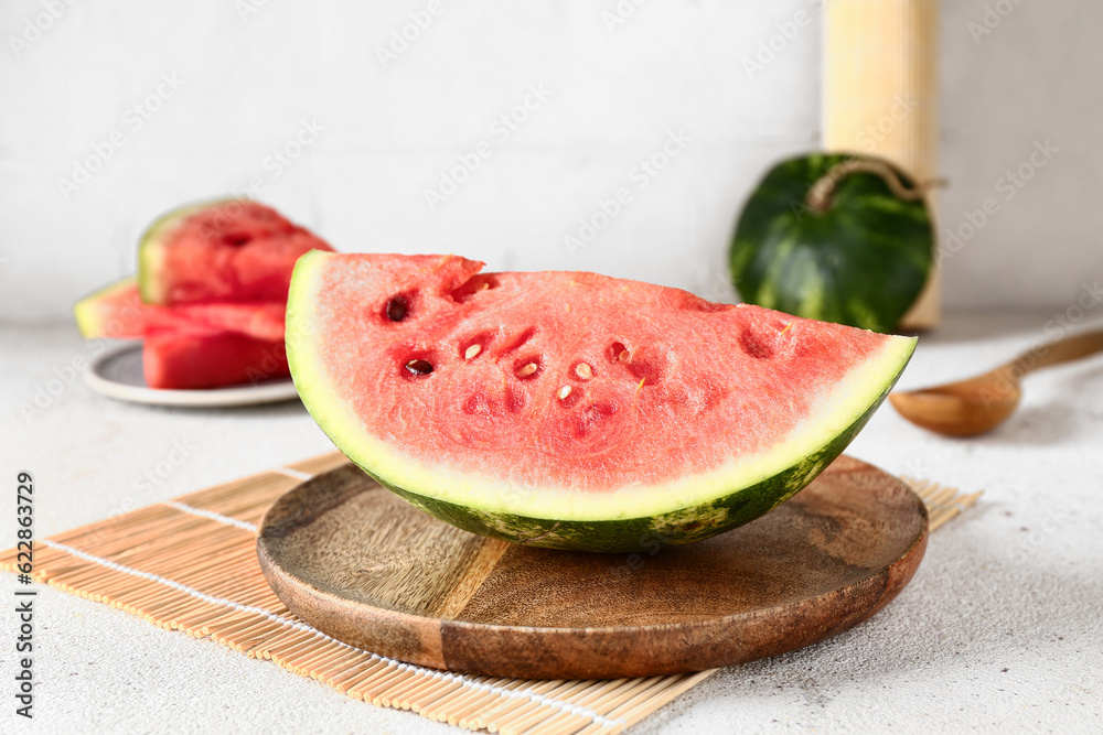 Wooden board with piece of fresh watermelon on white table