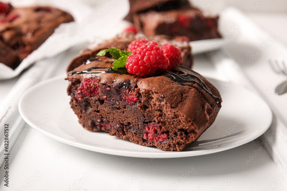 Plate with pieces of raspberry chocolate brownie on white background