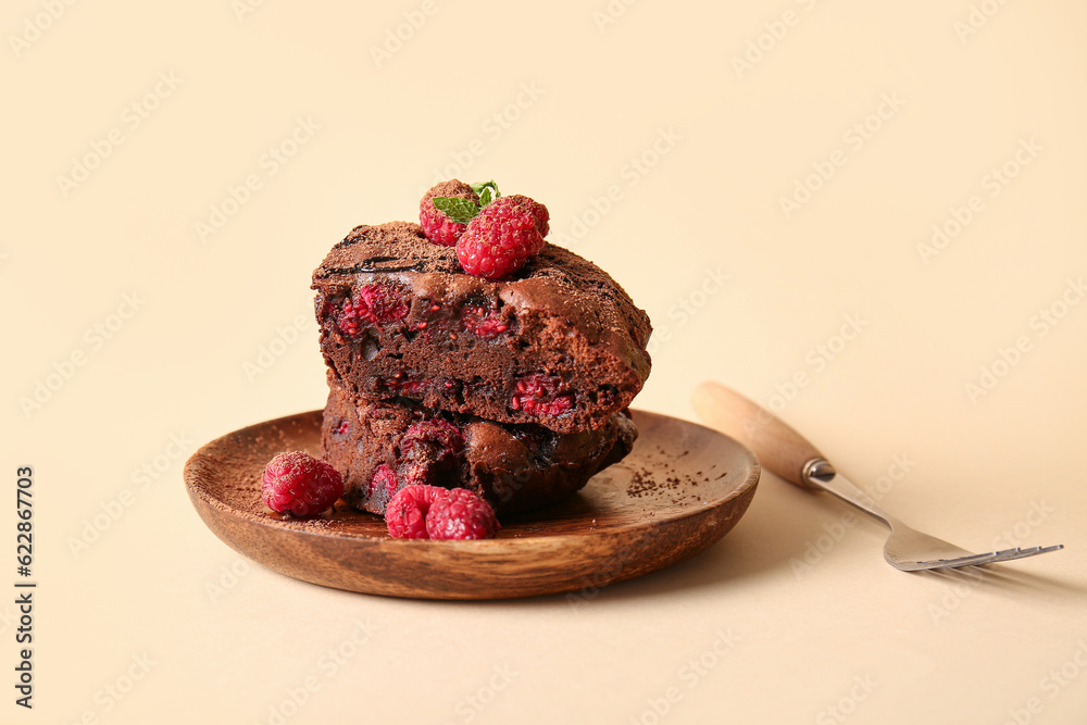 Wooden plate with pieces of raspberry chocolate brownie on orange background