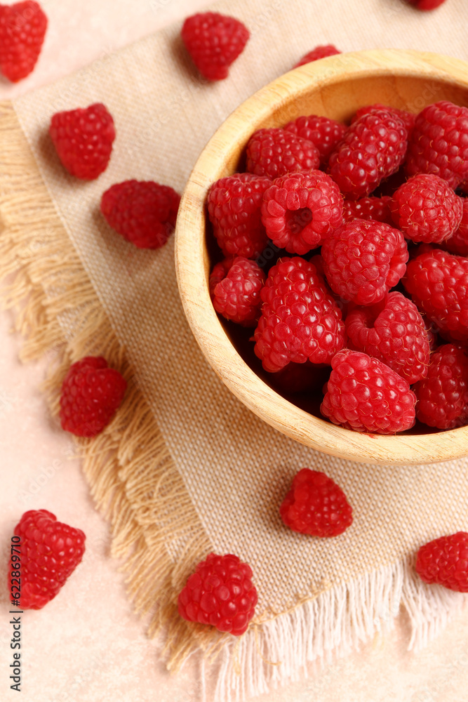 Wooden bowl with fresh raspberries on light background