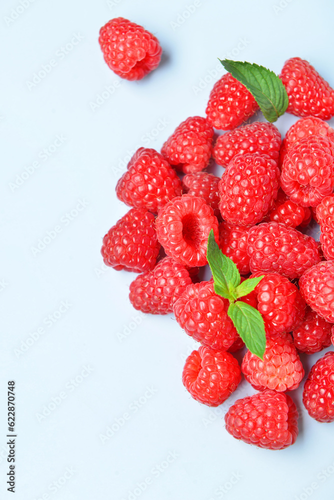 Heap of fresh raspberries and mint on blue background