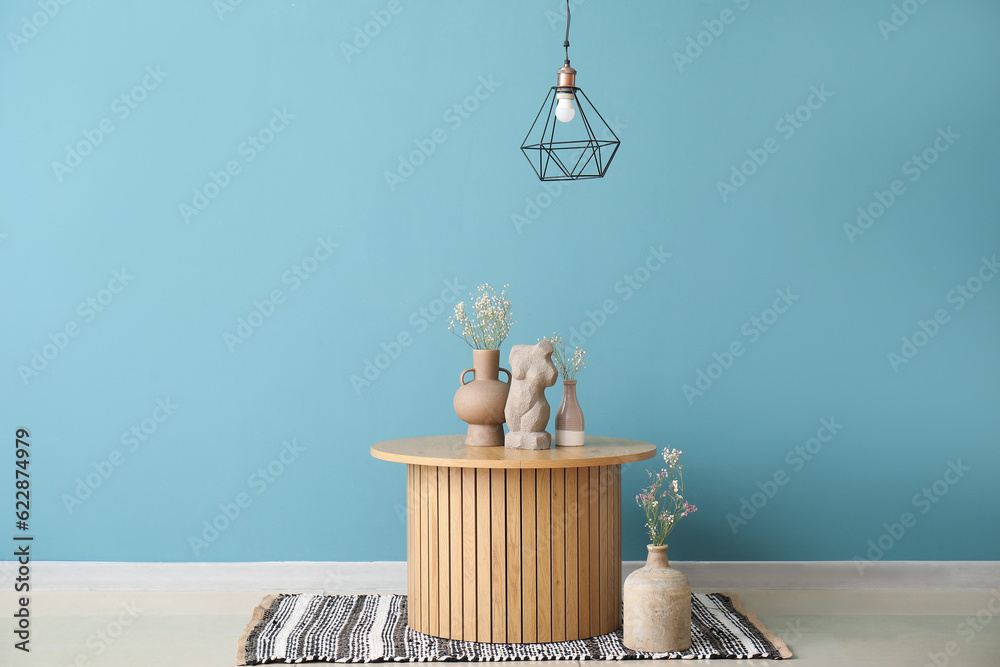 Coffee table with decor and gypsophila flowers in vases near blue wall