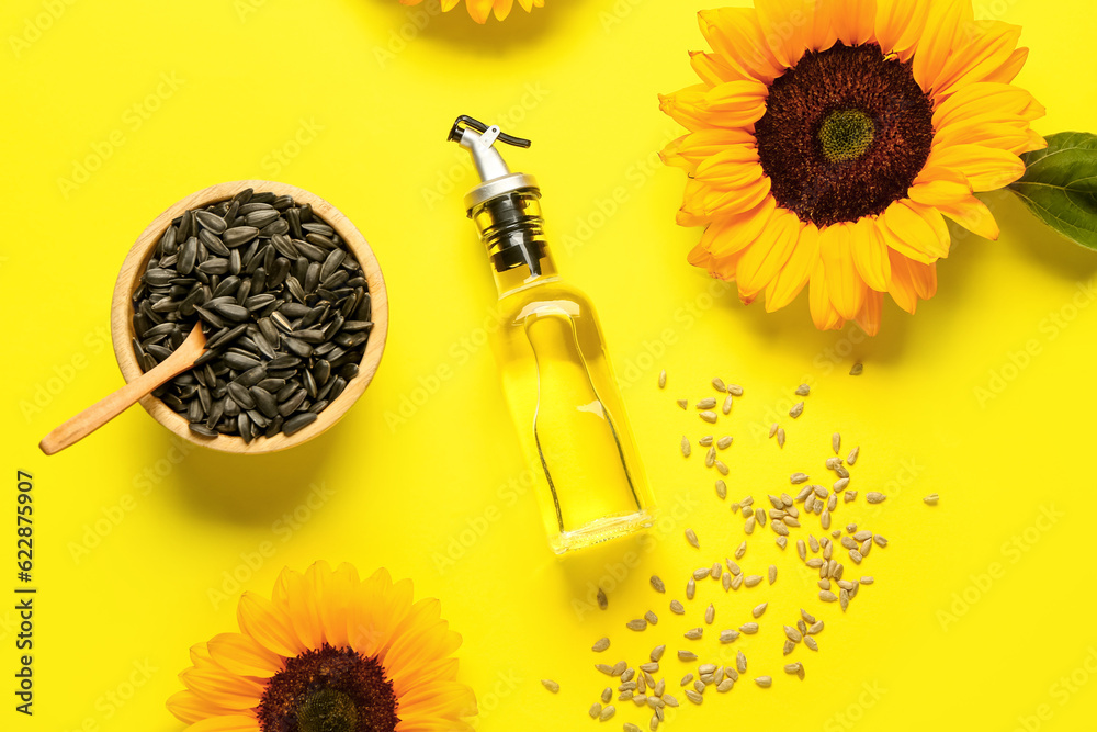 Sunflowers, seeds and bottle of oil on yellow background