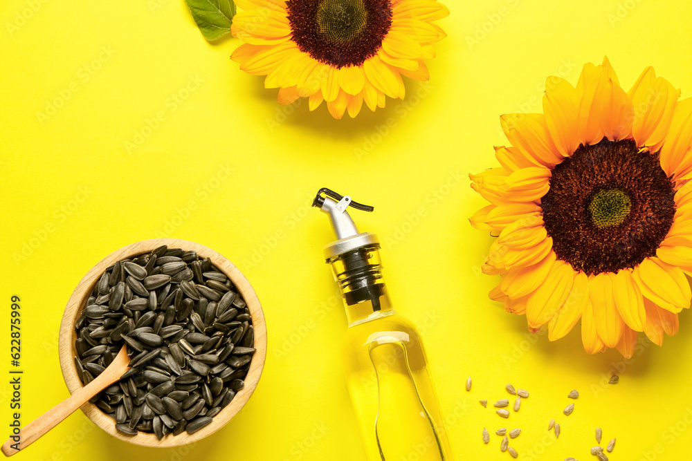 Sunflowers, seeds and bottle of oil on yellow background