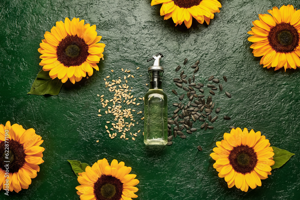 Sunflowers, seeds and bottle of oil on green background