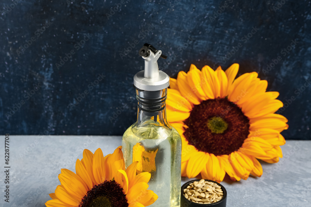 Sunflowers, seeds and bottle of oil on blue background