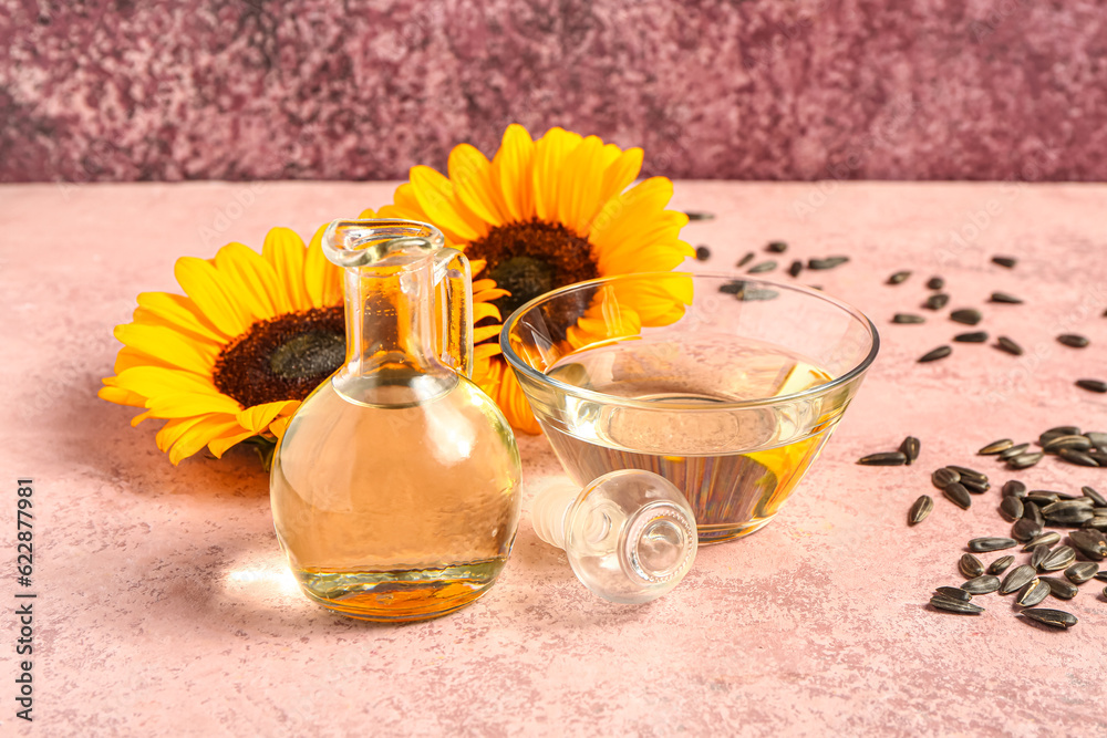 Sunflowers, seeds, bowl and decanter of oil on pink background