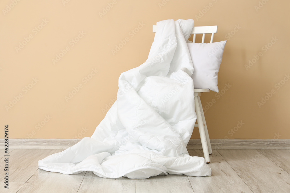 Chair with white blanket and pillow near beige wall