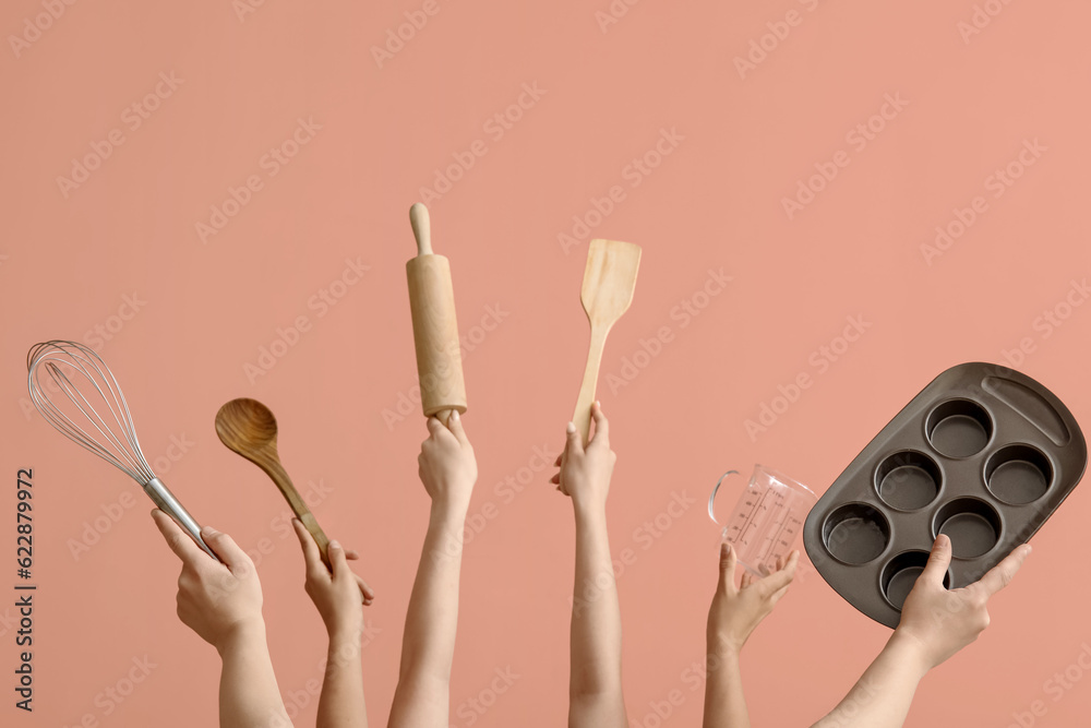 Female hands with baking utensils on pink background