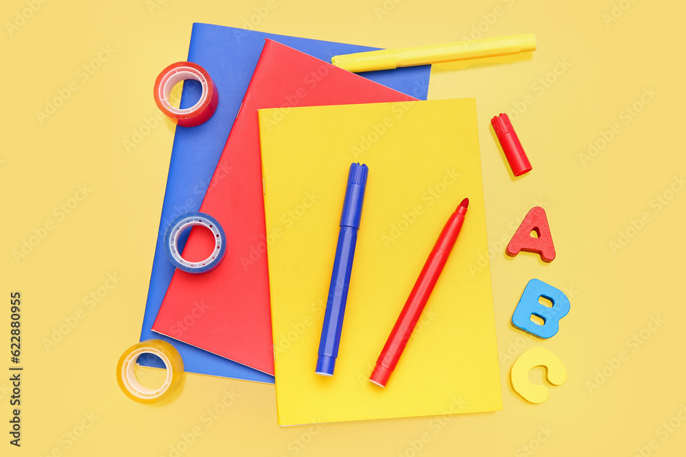 Notebooks with stationery on yellow background