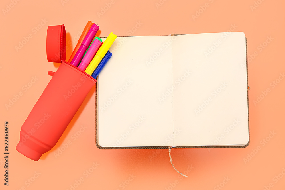 Blank notebook with stationery on orange background