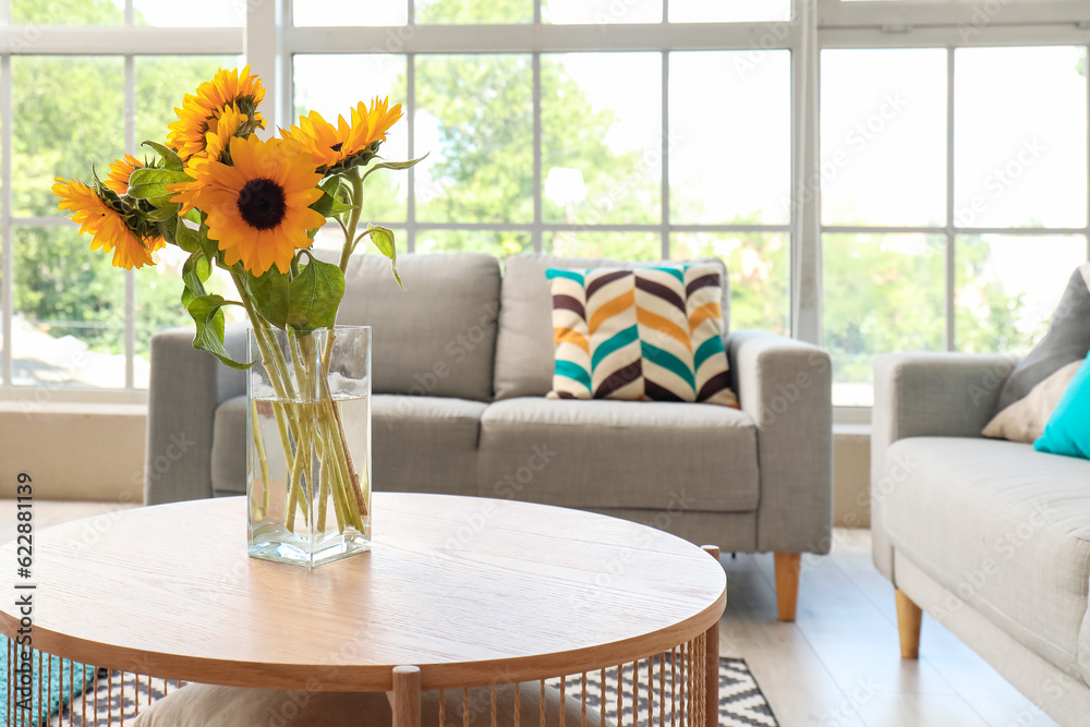 Vase with beautiful sunflowers on coffee table in interior of light living room