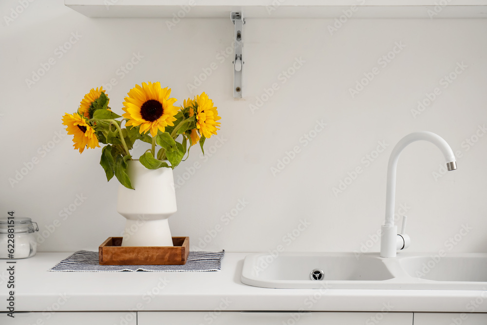 Vase with beautiful sunflowers on white kitchen counter