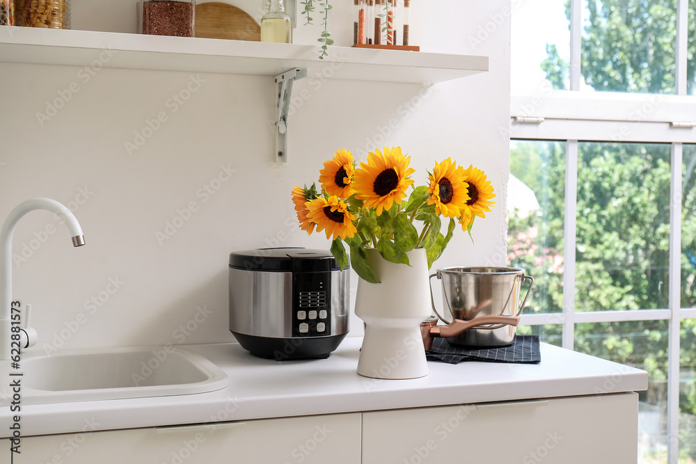 Vase with beautiful sunflowers on white kitchen counter