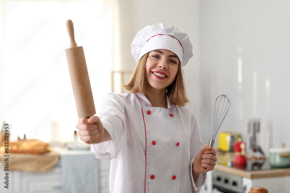 Female baker with rolling pin and whisk in kitchen