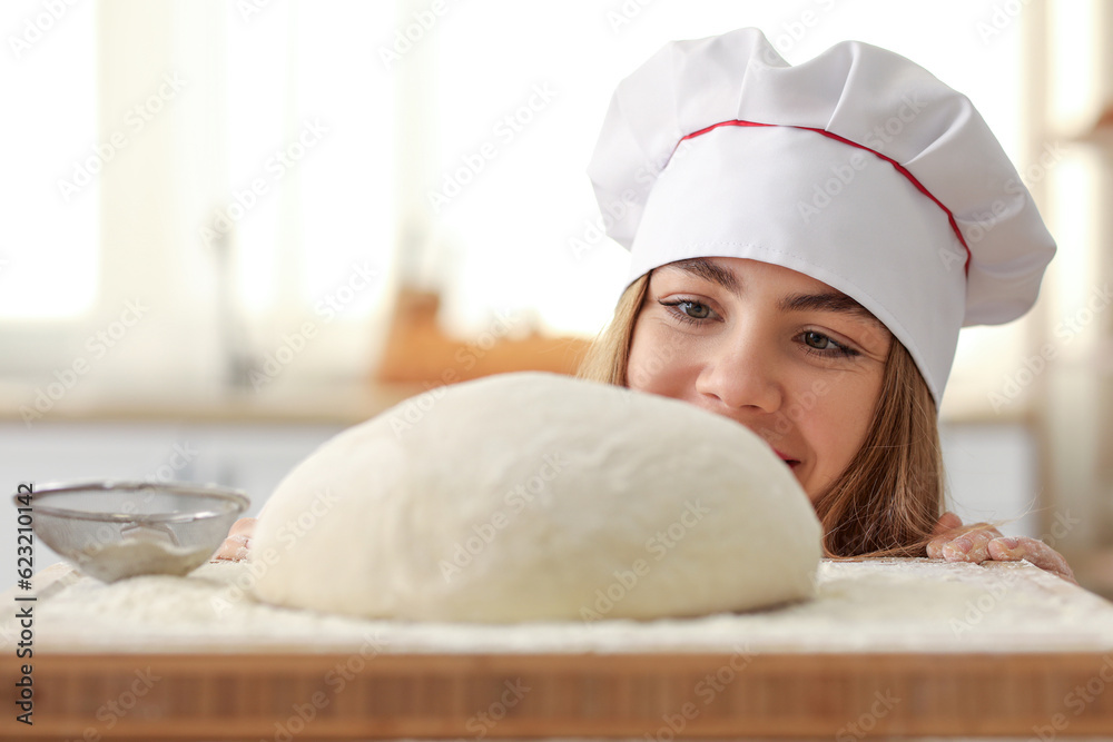 Female baker and raw dough on table in kitchen, closeup