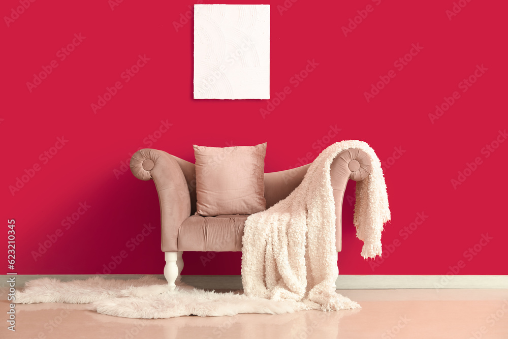 Stylish armchair with plaid and painting on pink wall