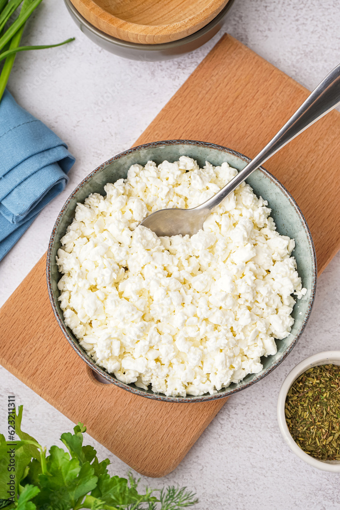 Bowl with tasty cottage cheese on light background