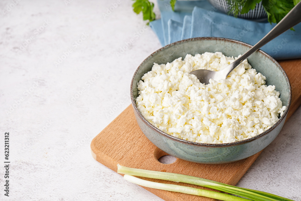 Bowl with tasty cottage cheese on light background