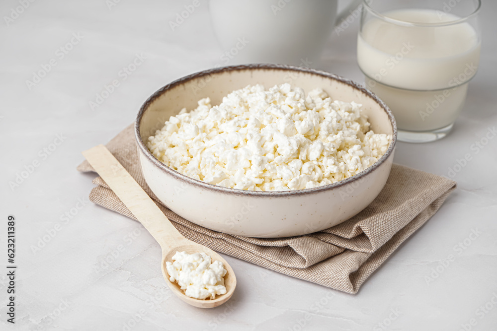 Bowl with tasty cottage cheese on light background