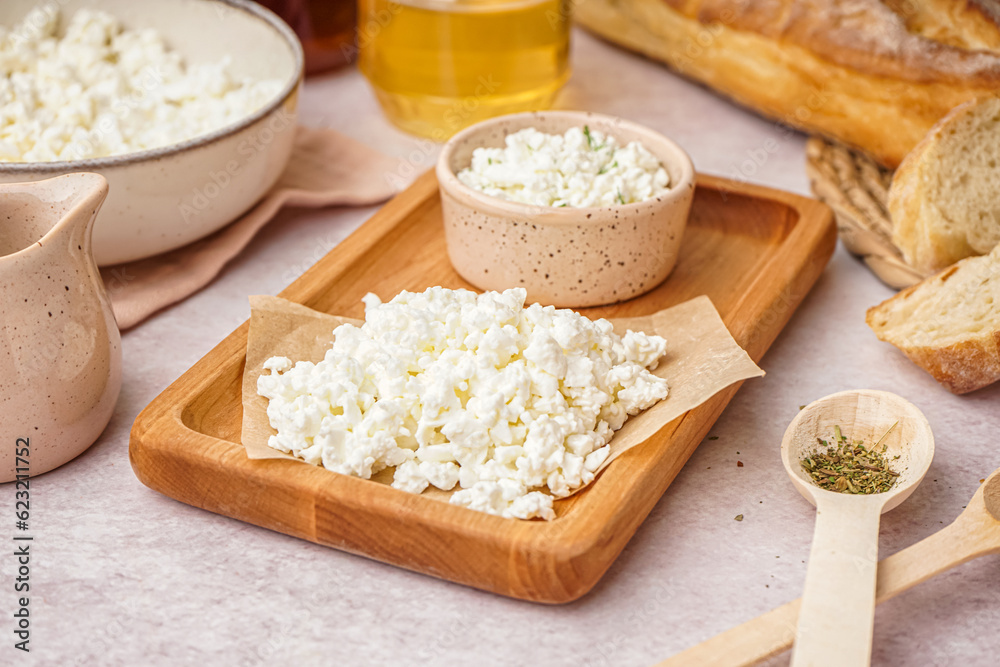 Wooden board with tasty cottage cheese on light background