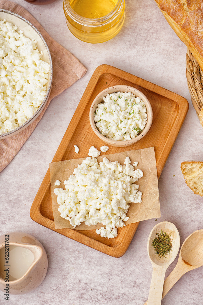 Wooden board with tasty cottage cheese on light background