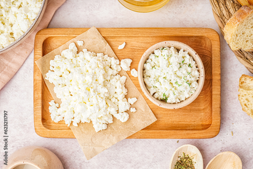 Wooden board with tasty cottage cheese on light background