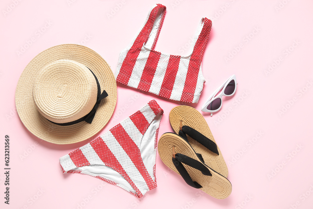 Stylish swimsuit, flip-flops, hat and sunglasses on pink background