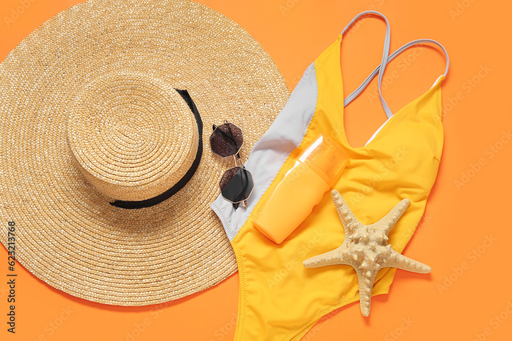 Stylish swimsuit, hat, sunglasses, bottle of sunscreen cream and starfish on color background