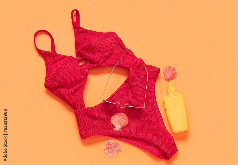 Stylish swimsuit, sunglasses, bottle of sunscreen and seashells on color background