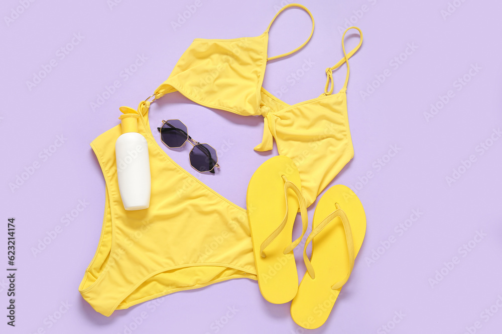 Stylish swimsuit, sunglasses, flip-flops and bottle of sunscreen on color background