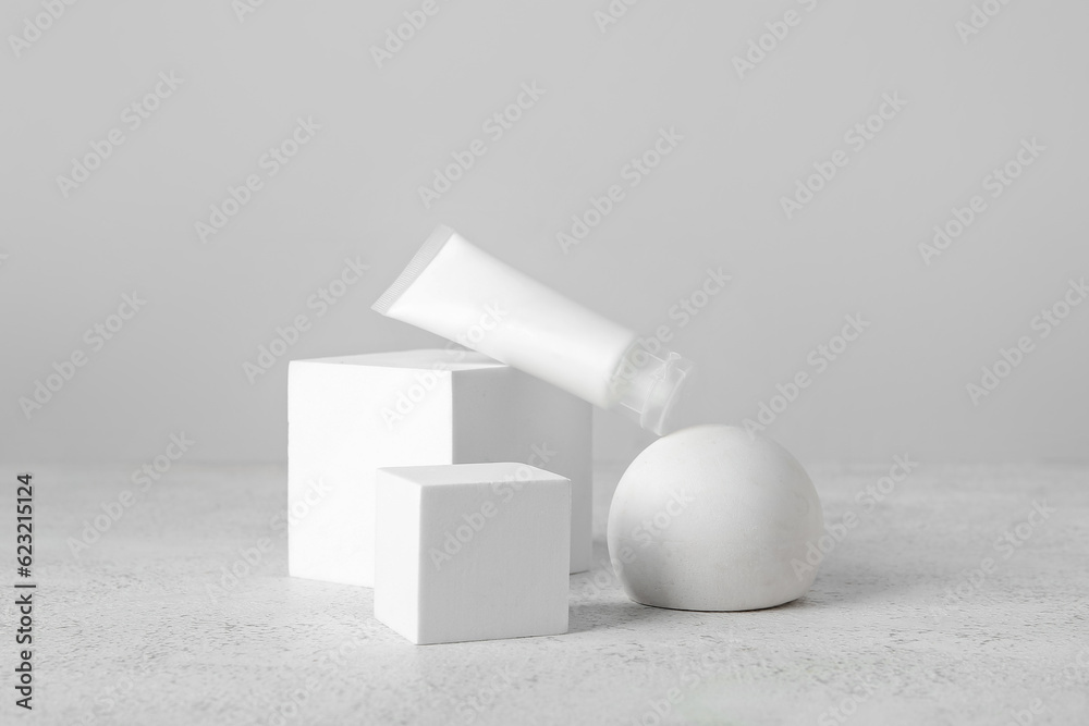 Composition with tube of cosmetic product and plaster podiums on light background