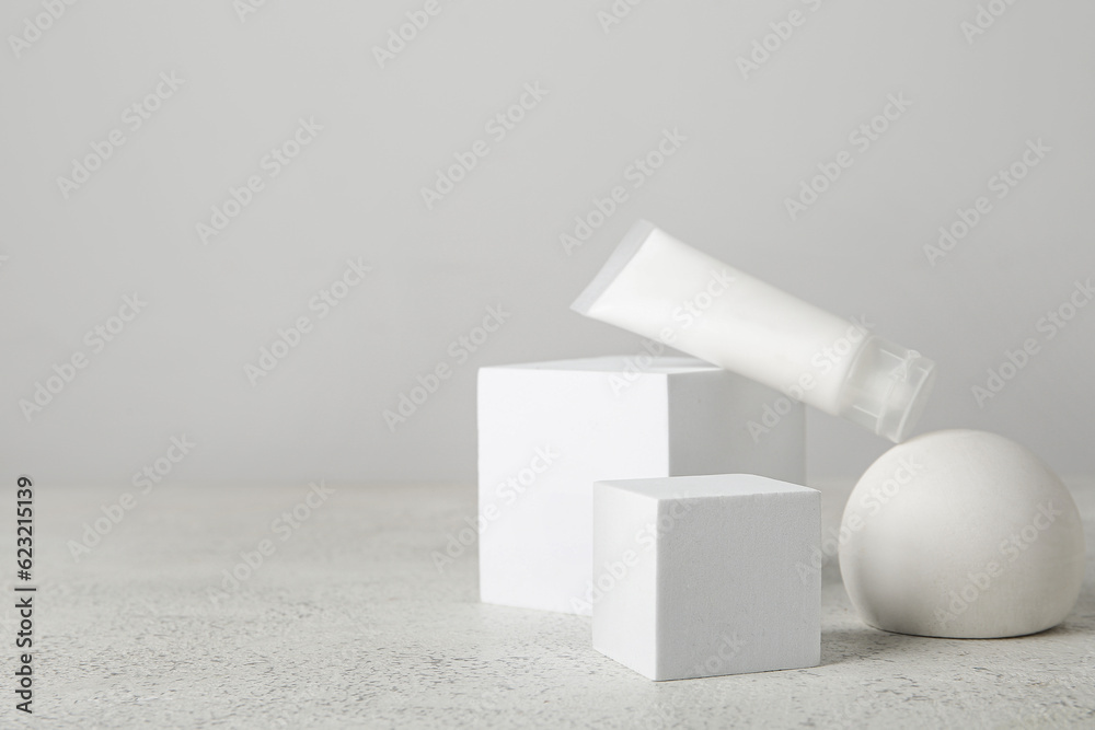 Composition with tube of cosmetic product and plaster podiums on light background