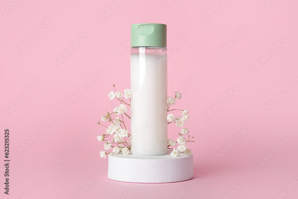 Composition with bottle of cosmetic product, plaster podium and gypsophila flowers on pink backgroun