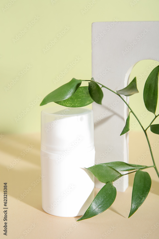 Bottle of cosmetic product, plaster decor and plant branch on color background