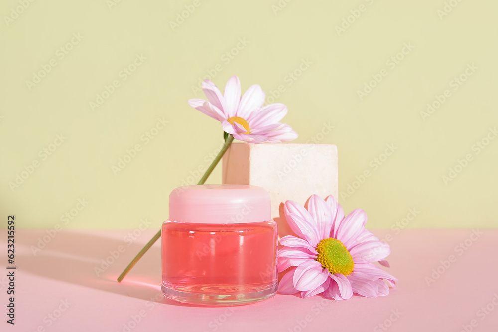 Jar of cosmetic product, plaster podium and flowers on color background