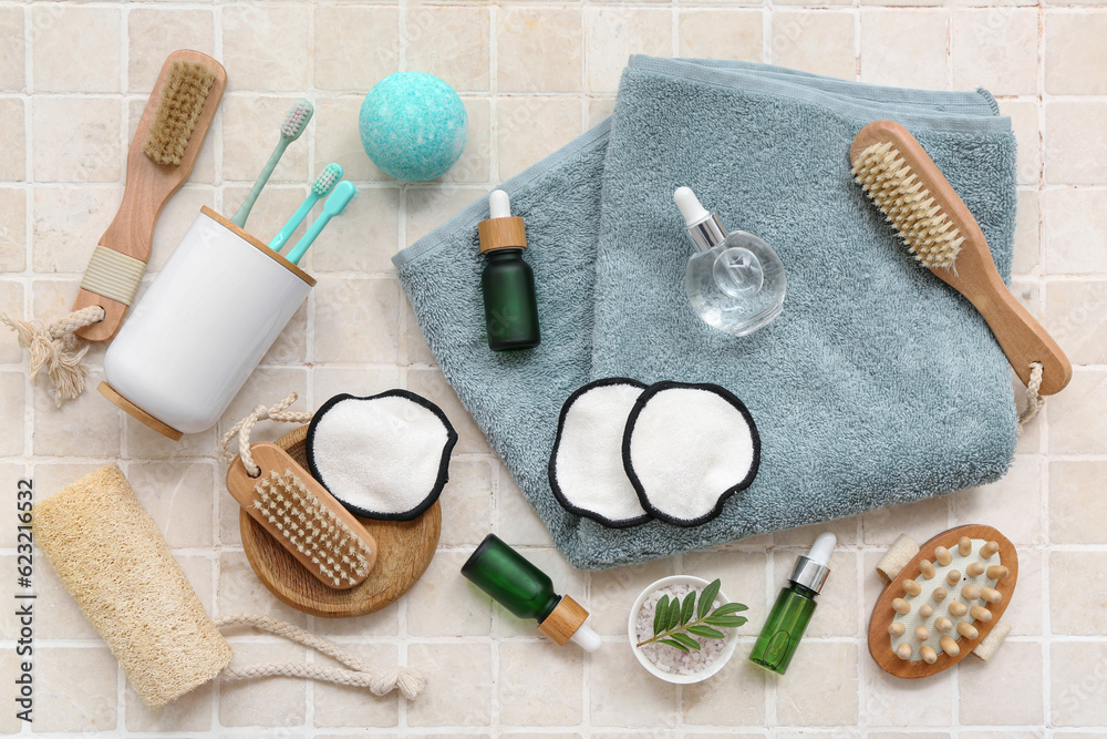 Composition with different bath accessories and cosmetics on light tile background